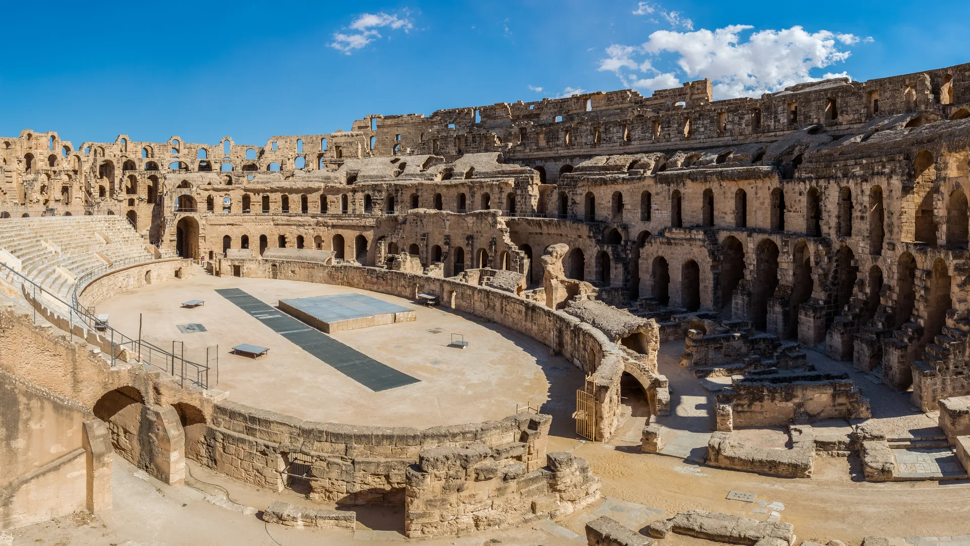 Velký římský amfiteátr v El Jem ve zlatavém kameni pod modrou oblohou